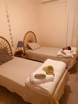 A hotel room with two single beds, a bedside table with a lamp, and a wall-mounted decoration. - Apartment 'Casa Kapano' with Mountain View, Wi-Fi and Air Conditioning (La Cala de Mijas)