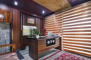 Un comptoir d'accueil avec une enseigne indiquant « OYO », une plante en pot, un téléphone et un tableau encadré accroché au mur.