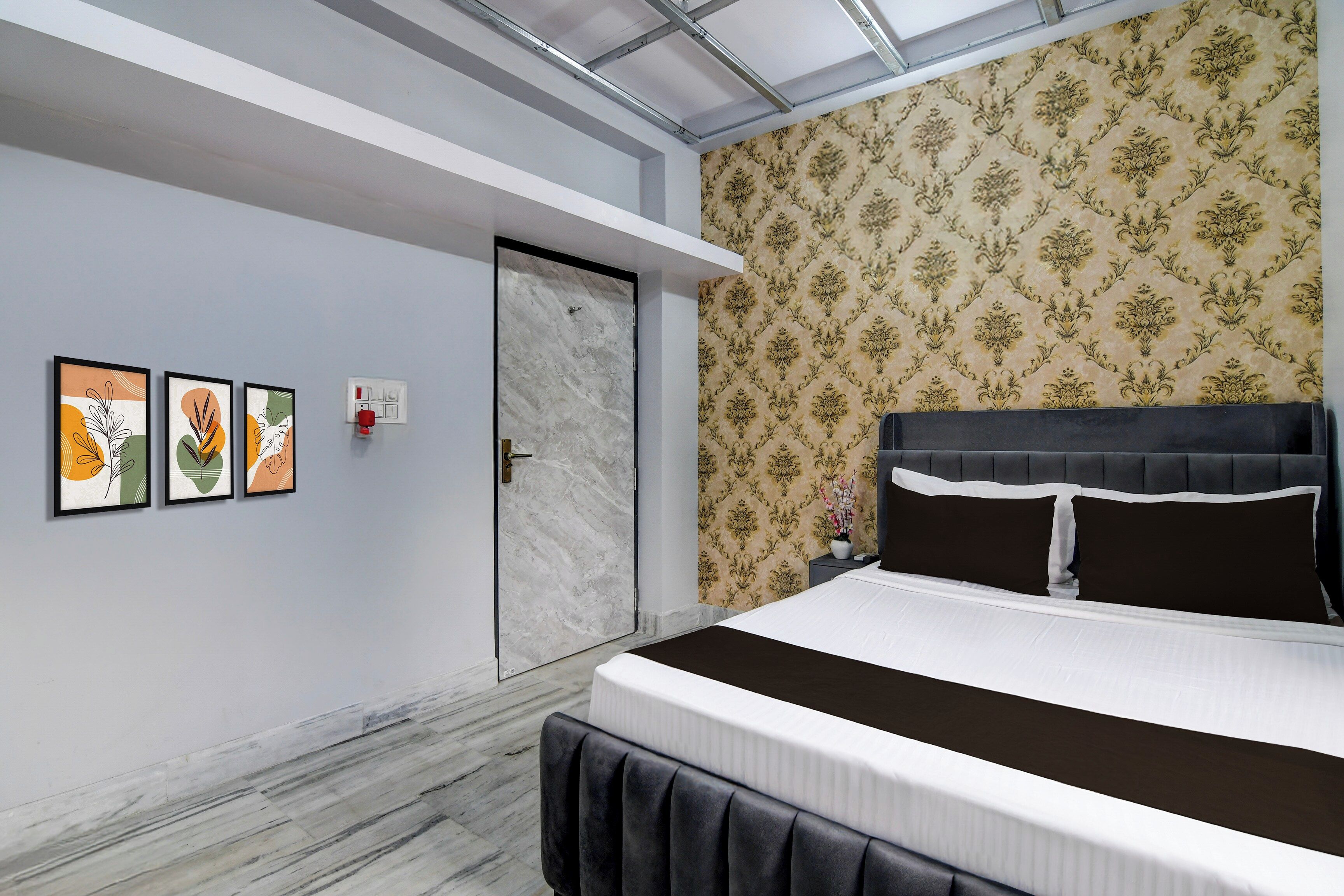 A bedroom with a bed, a door, and three framed artworks on the wall.