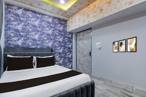Une chambre à coucher avec un lit, une table de chevet, une porte et des œuvres d’art murales.
