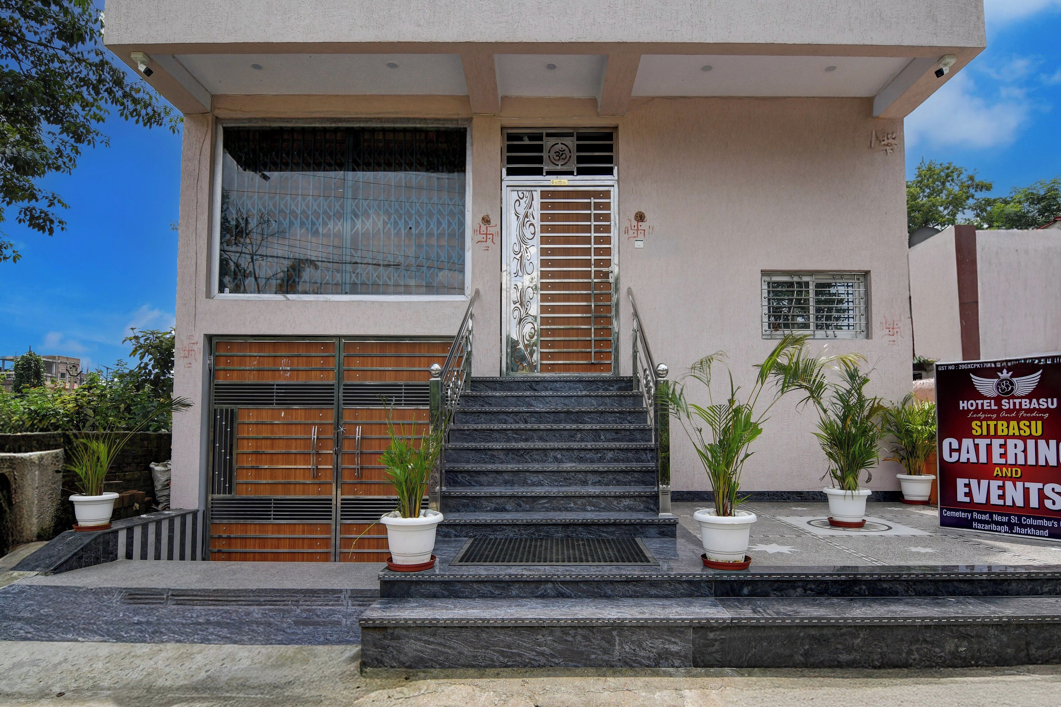 A hotel entrance with a staircase, a wooden door, and a signboard advertising catering and events.