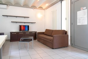Una sala de estar moderna con un sofá, una mesita, un mueble aparador y un televisor.