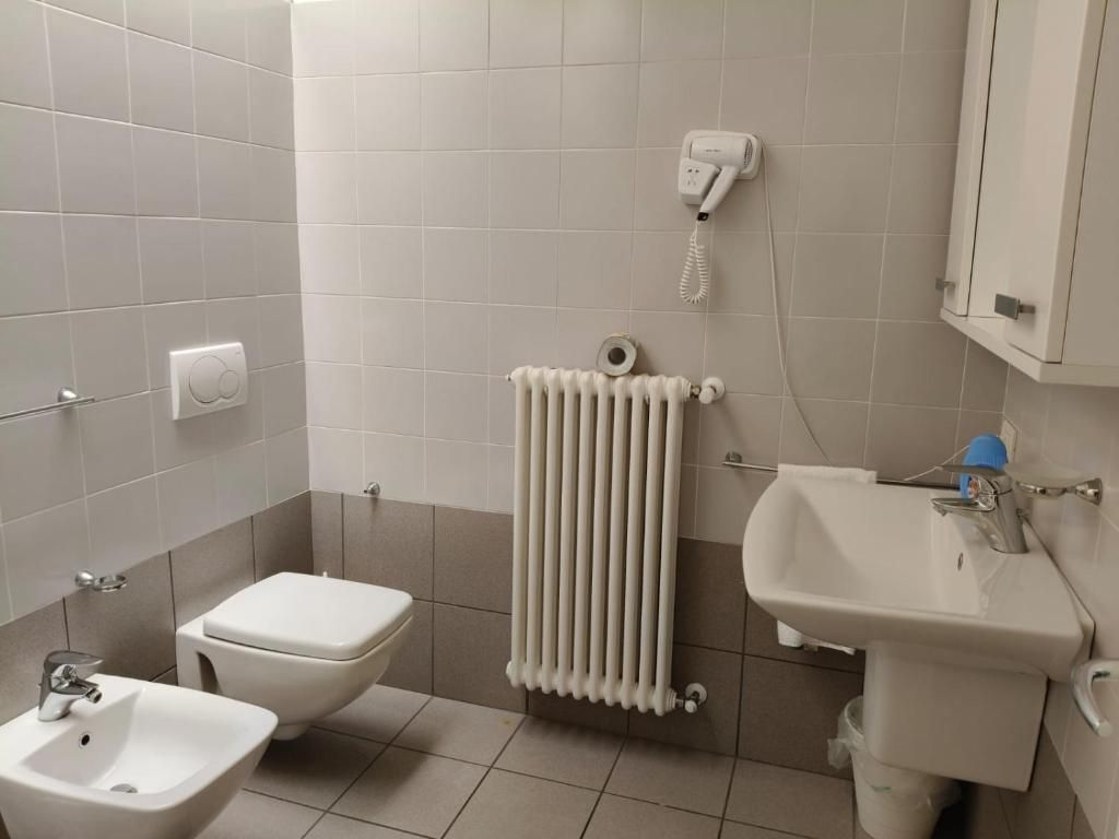 A bathroom with a toilet, bidet, sink, and a wall-mounted telephone.