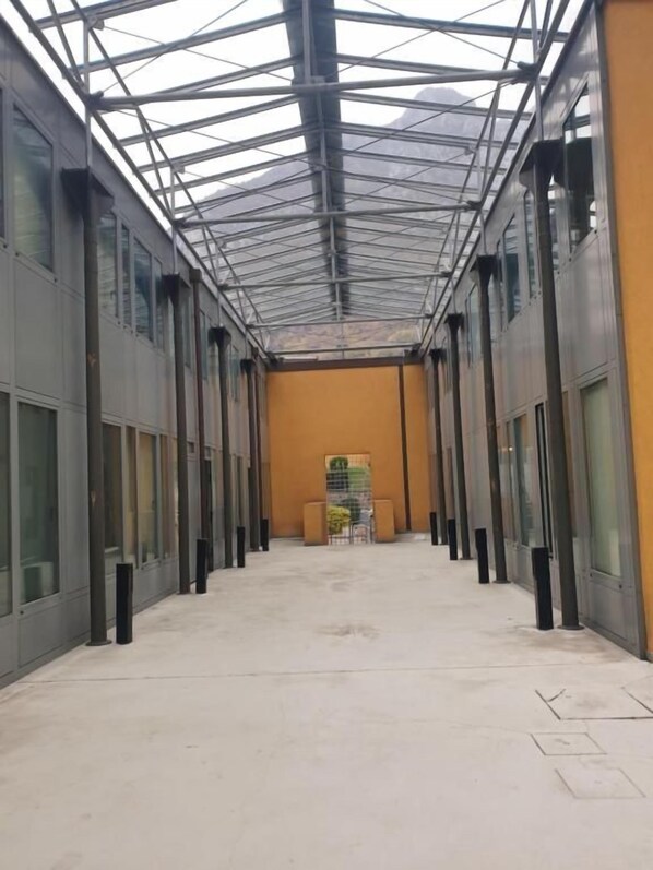 A corridor with a glass ceiling, metal beams, and a concrete floor. - Appattamento per LAVORATORI wifi gratis (Lecco)