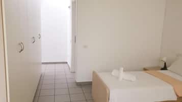 Un dormitorio con cama, mesita de noche y puerta que da a otra habitación.