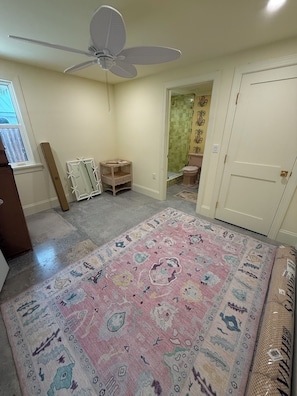 A room with a ceiling fan, a patterned rug, a door, and a window. - Spoonbill Cottage | 3-Min Walk to Beach | Heated Pool | 4BR Family Retreat (Bradenton Beach)