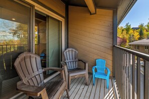 A wooden deck with two Adirondack chairs and a blue chair. - Sunrise 304 – Spacious Mountain Retreat Near Steamboat Resort! (Steamboat Springs)