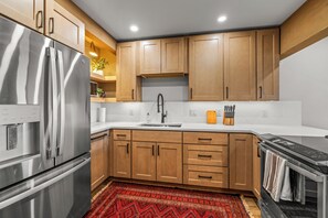 A modern kitchen with stainless steel appliances, wooden cabinets, and a marble countertop. - Sunrise 304 – Spacious Mountain Retreat Near Steamboat Resort! (Steamboat Springs)