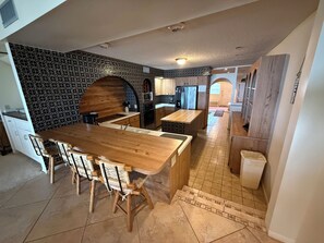 A modern kitchen with a wooden island, built-in appliances, and a patterned backsplash. - An Island Time | Direct Beachfront | 2BR Upstairs Retreat | Old Florida Charm (Holmes Beach)