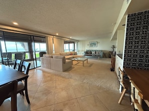 A spacious living area with a large sofa, a dining table, and a kitchen area with a patterned backsplash. - An Island Time | Direct Beachfront | 2BR Upstairs Retreat | Old Florida Charm (Holmes Beach)