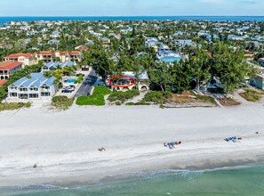 A coastal residential area with houses, a beach, and a clear view of the ocean. - An Island Time | Direct Beachfront | 2BR Upstairs Retreat | Old Florida Charm (Holmes Beach)