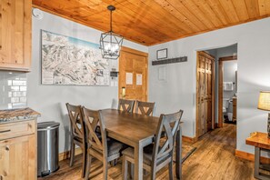 A dining area with a wooden table and chairs, a map on the wall, and a wooden ceiling. - Top-floor ski-in/ski-out retreat with stunning gondola views and private balcony (Steamboat Springs)