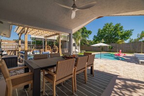 Um terraço ao ar livre com piscina, móveis de vime e ventilador de teto.