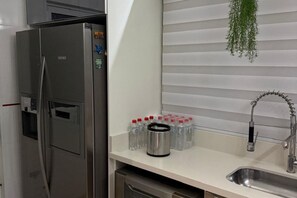 A kitchen with a stainless steel refrigerator, a sink with a modern faucet, and a countertop with water bottles and a thermos. - New Listing (São José dos Pinhais)