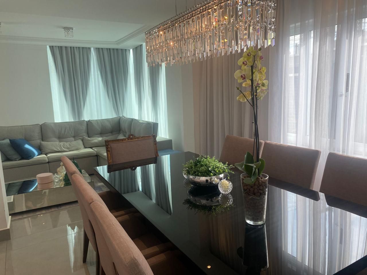 Een moderne woonkamer met een bank, een eettafel en een kroonluchter.