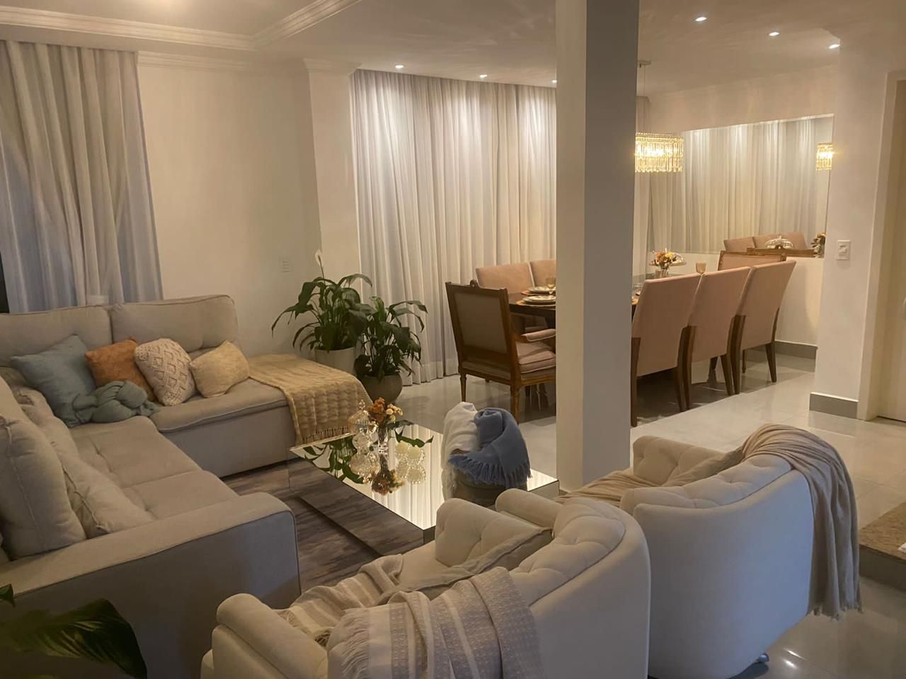 Een moderne woonkamer met een zithoek, een salontafel met een vaas, en een eetgedeelte met stoelen en een tafel.