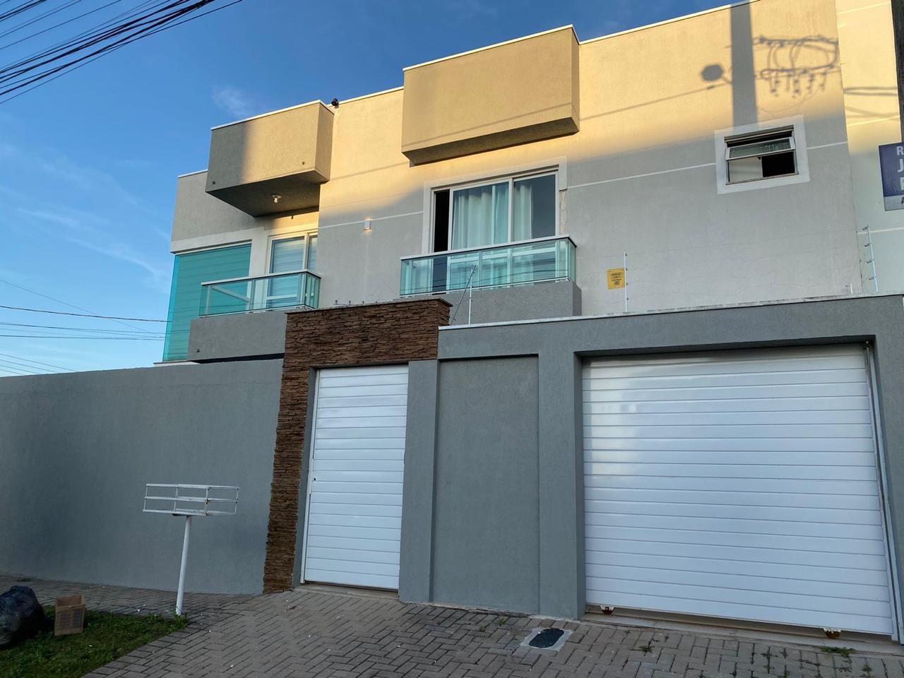 Un edificio moderno con dos puertas de garaje, un muro de ladrillo y un cielo despejado.