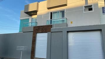 Un edificio moderno con dos puertas de garaje, un muro de ladrillo y un cielo despejado.