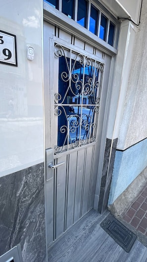 Una reja de metal con un diseño decorativo, una placa de números y un pequeño ventanal con barrotes.