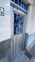 Una reja de metal con un diseño decorativo, una placa de números y un pequeño ventanal con barrotes.