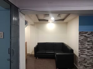 Una habitación con un sofá de cuero negro, una lámpara en el techo y una pared con diseño.