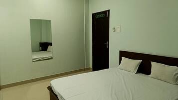Quarto de hotel com cama, espelho, porta e interruptor de luz.