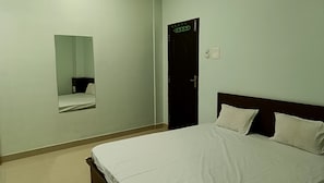 Una habitación de hotel con cama, espejo, puerta y un interruptor de luz.
