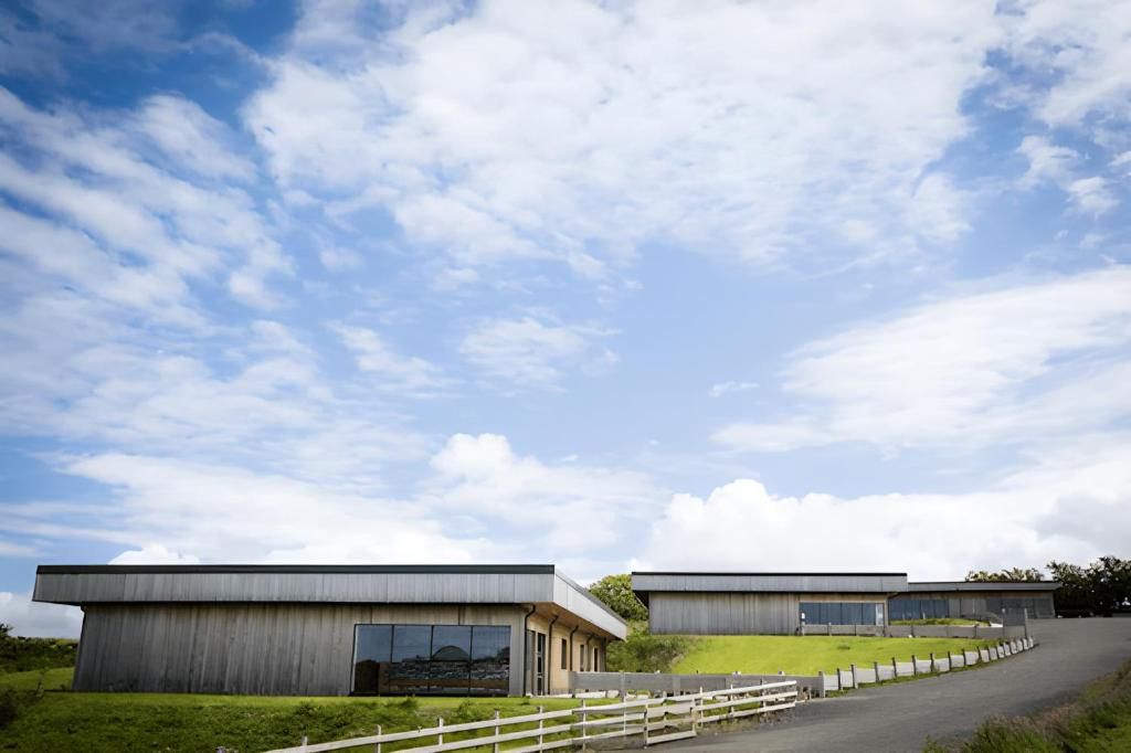 Two modern buildings with large windows and a grassy area in front.