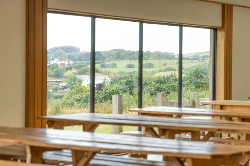 A room with large windows offering a view of a green landscape and a distant house.