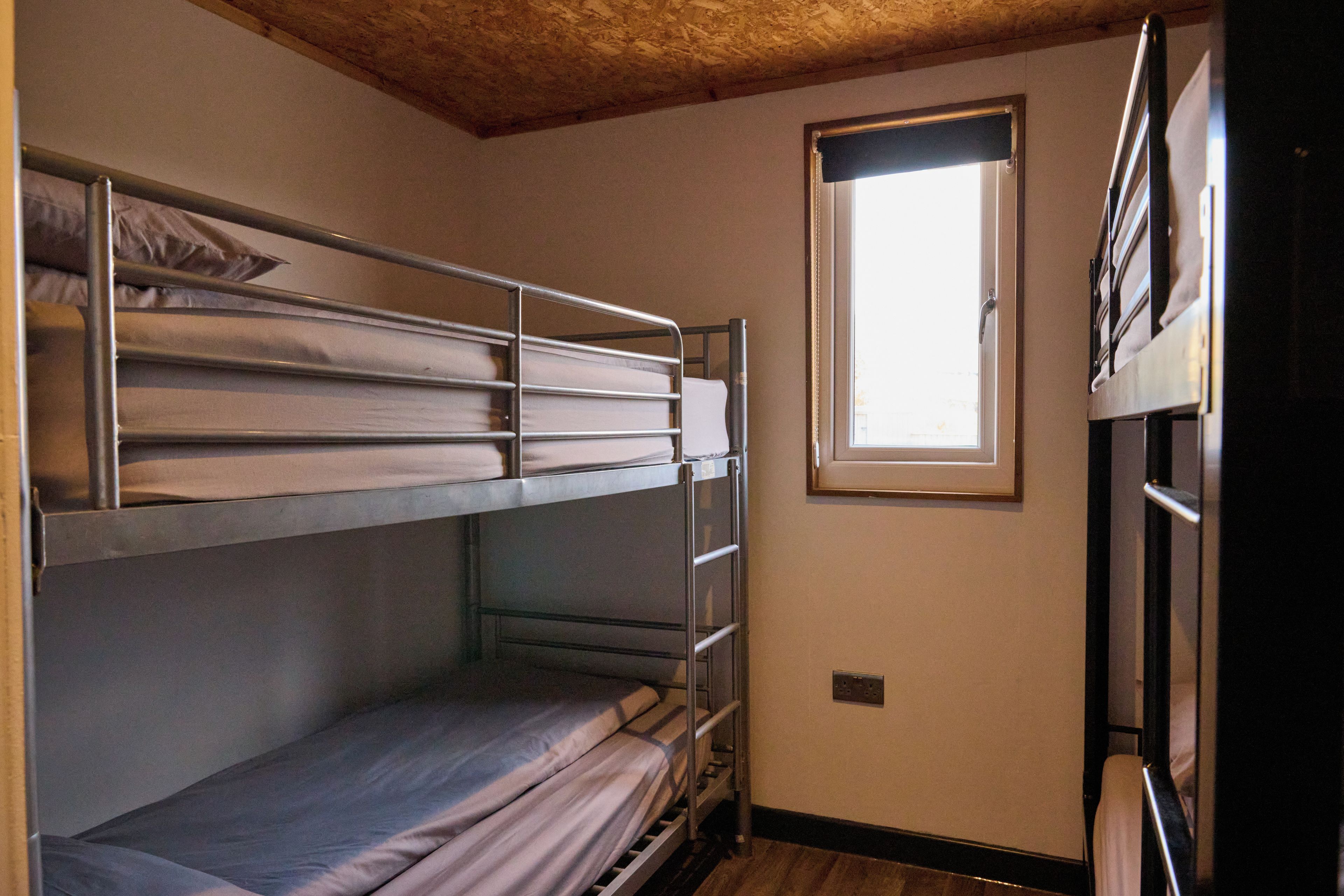 Een slaapkamer met stapelbed, een raam en een deur.