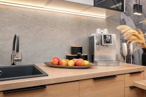 Eine moderne Küche mit Spüle aus Edelstahl, einer Kaffeemaschine und einer Obstschale.