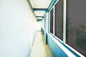 A corridor with doors on one side and windows on the other. - Super Hotel O Vibrant Residency (Ahmedabad)