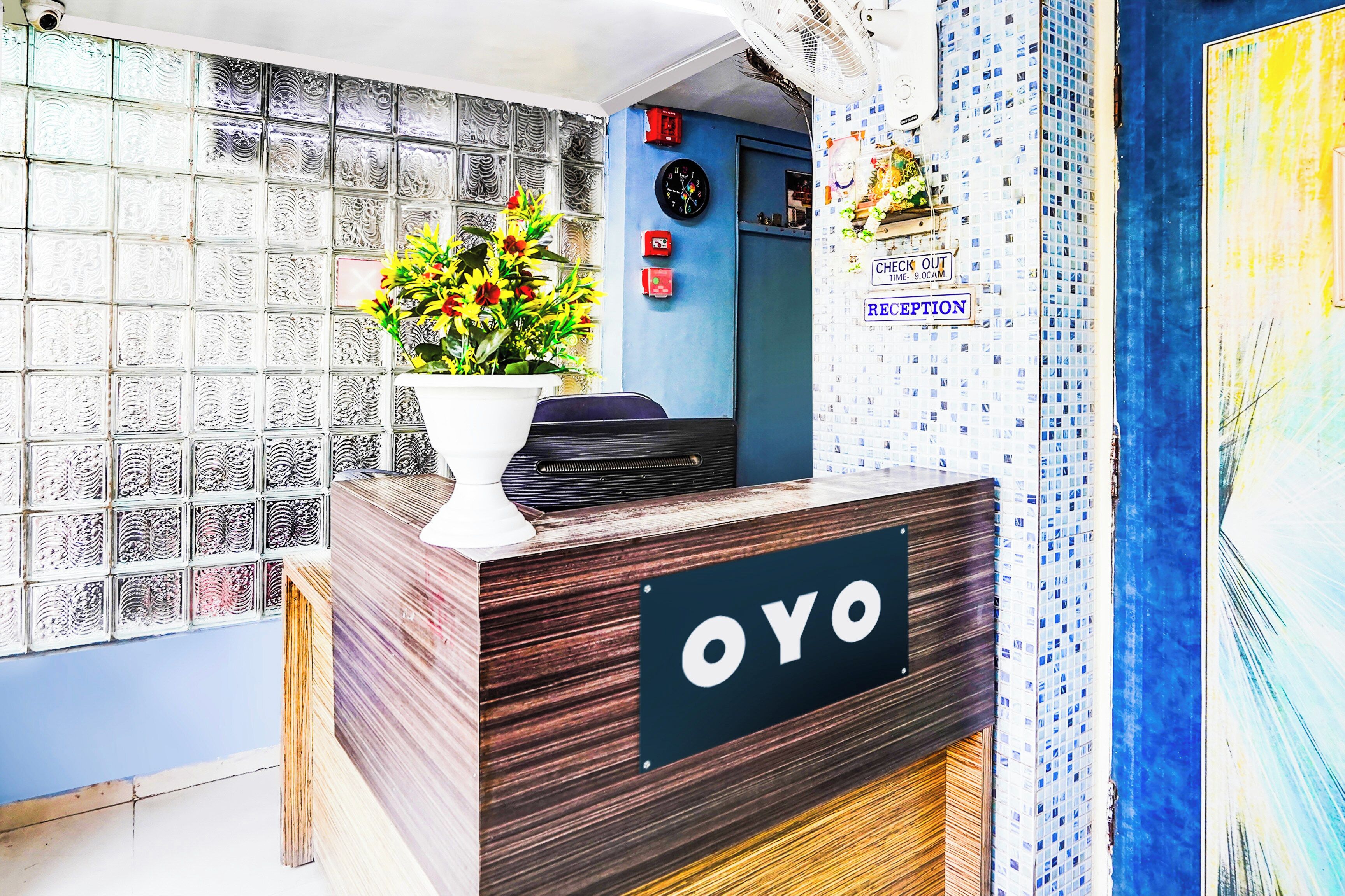 Ein Empfangsschalter mit einem 'OYO'-Schild, einer Uhr und einem 'CHECK OUT'-Schild, das eine Zeitgrenze von 9:00 Uhr anzeigt.