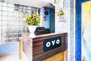 A reception desk with a 'OYO' sign, a clock, and a 'CHECK OUT' sign indicating a 9:00 AM time limit. - Super Hotel O Vibrant Residency (Ahmedabad)