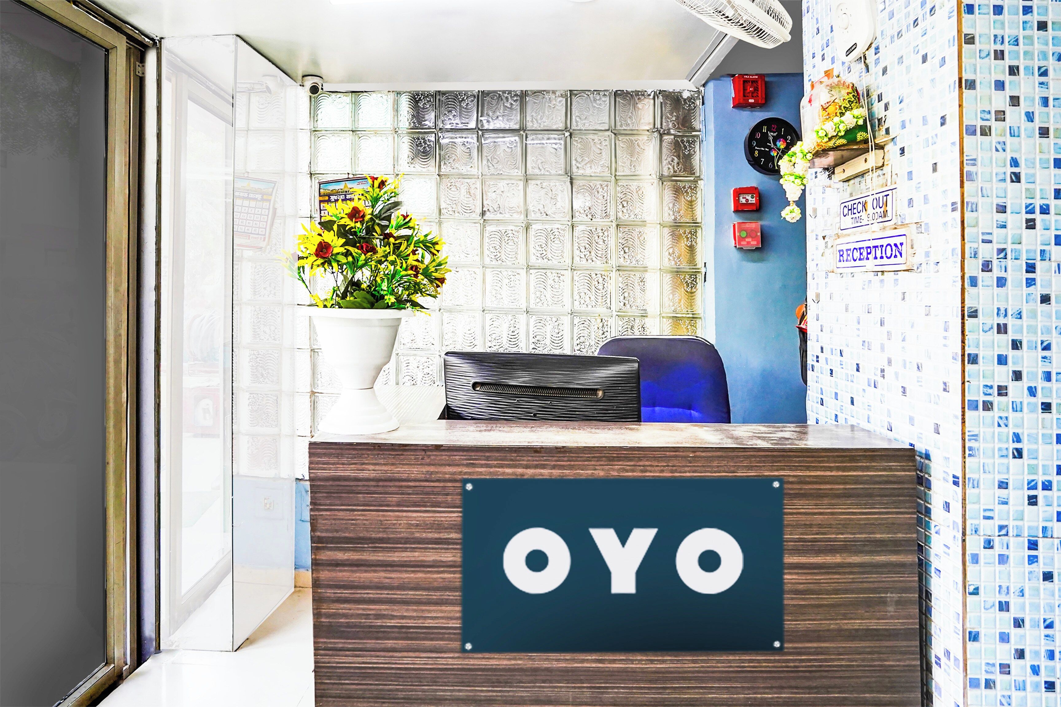 A reception desk with a sign that reads 'OYO' and a potted plant with yellow flowers.