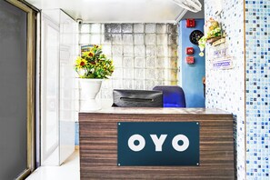 Una recepción con un letrero que dice 'OYO' y una planta en maceta con flores amarillas.