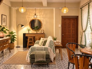 A cozy living room with a sofa, a dining table, chairs, a coffee table, a lamp, a mirror, and hanging lights. - Tranquil 2-bedroom house with AC in charming Wat Ket Chiang Mai (Chang Wat Chiang Mai)