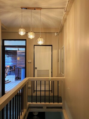 A staircase with a railing, a door, and pendant lights. - Tranquil 2-bedroom house with AC in charming Wat Ket Chiang Mai (Chang Wat Chiang Mai)
