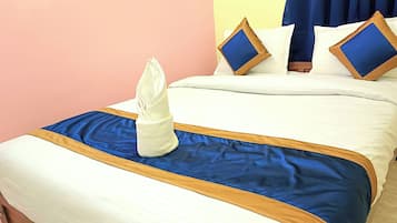 Ein ordentlich bezogenes Bett mit einer blau-weißen Tagesdecke, ein gefaltetes weißes Handtuch und zwei Kissen mit blauen und braunen Akzenten.