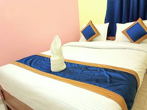 Ein ordentlich bezogenes Bett mit einer blau-weißen Tagesdecke, ein gefaltetes weißes Handtuch und zwei Kissen mit blauen und braunen Akzenten.