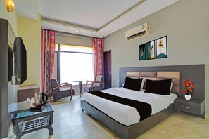 A hotel room with a bed, a desk, a chair, a TV, and a window with curtains. - Townhouse by OYO Patiala-Zirakpur (Zirakpur)