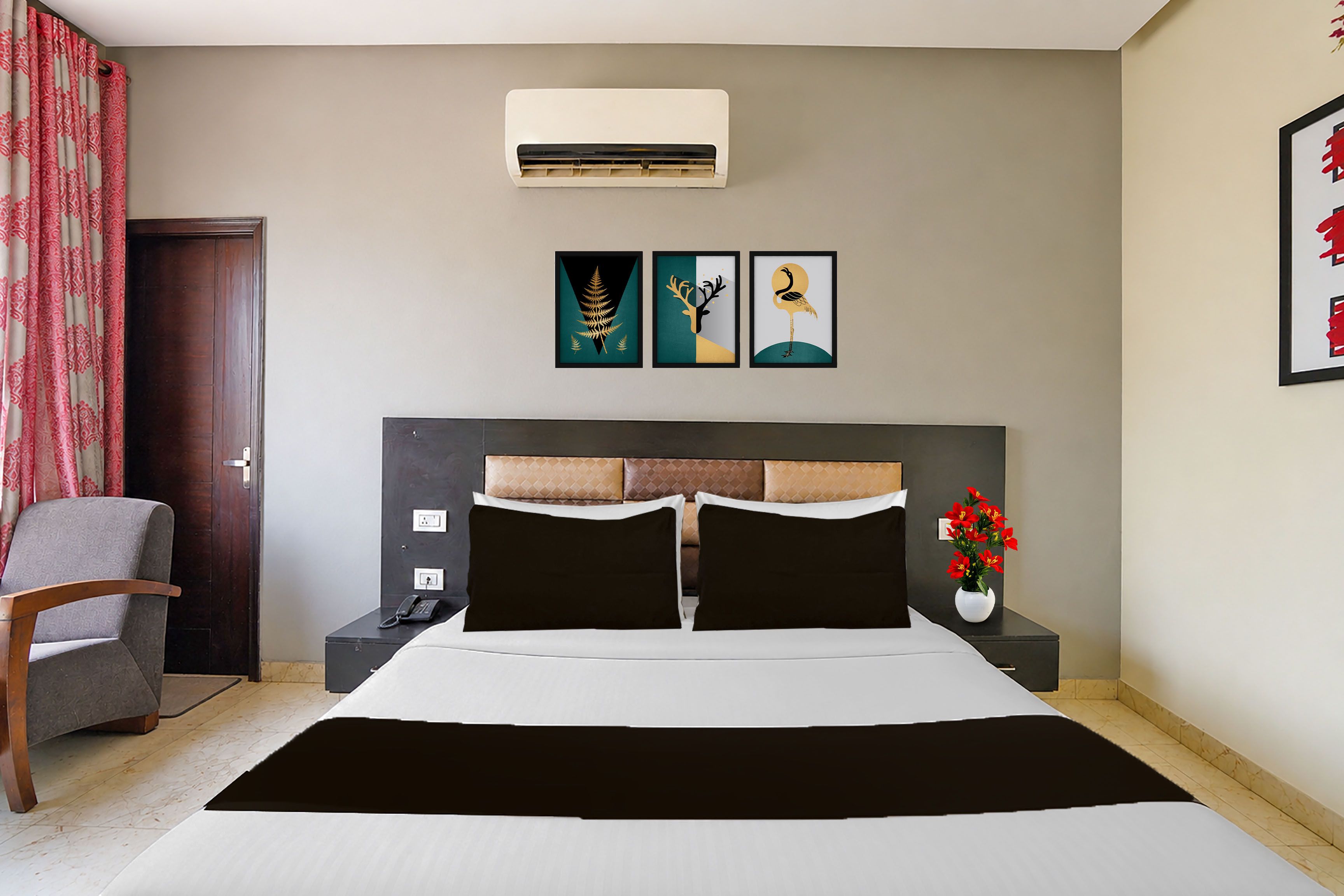 Habitación de hotel con cama, mesitas de noche, una silla, aire acondicionado y una obra de arte en la pared.