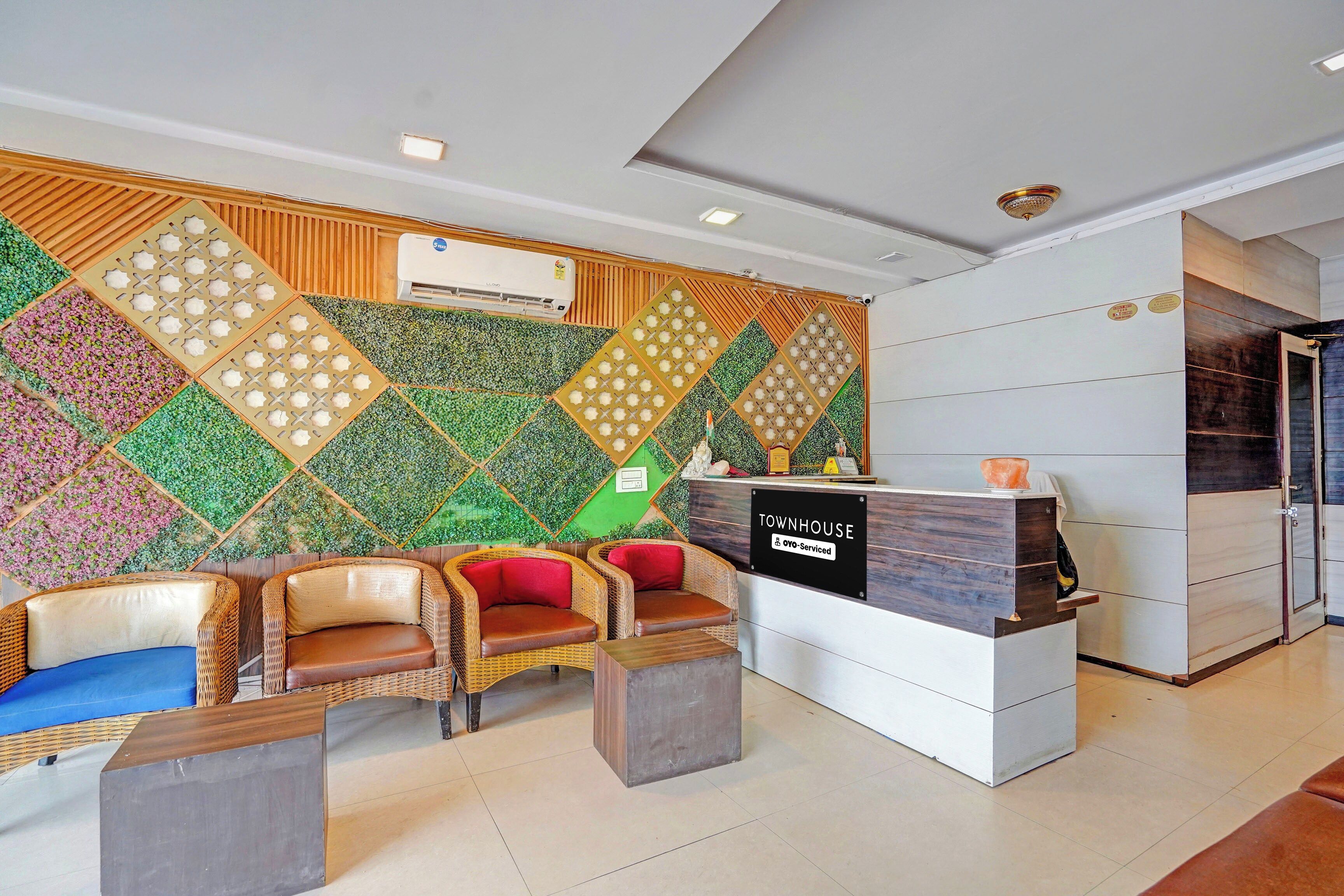 A reception area with a modern design, including a reception desk, seating area with wicker chairs, and a decorative wall with geometric patterns.