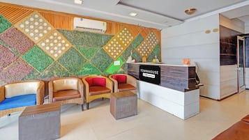 A reception area with a modern design, including a reception desk, seating area with wicker chairs, and a decorative wall with geometric patterns.