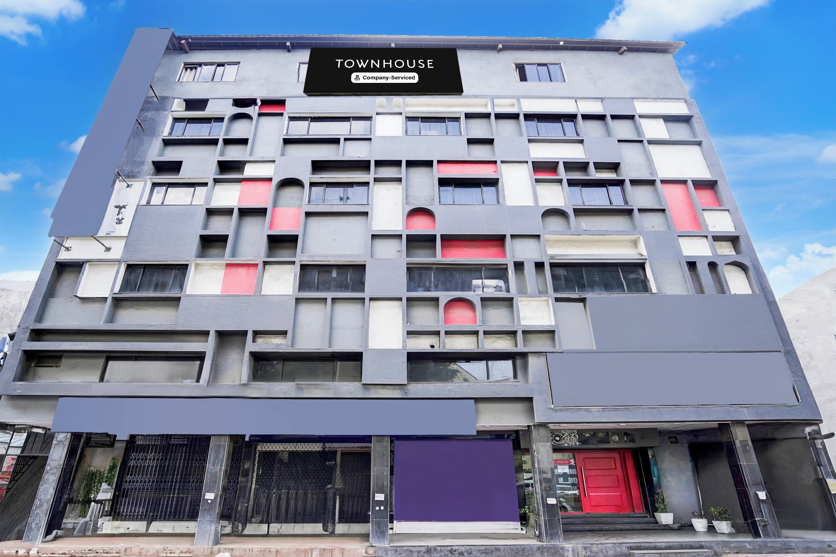 A multi-story building with a sign reading 'TOWNHOUSE Company Serviced'.