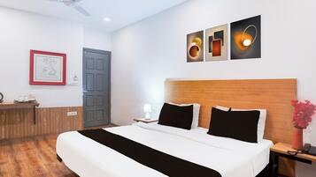 A hotel room with a bed, bedside table, lamp, and a wall-mounted artwork.