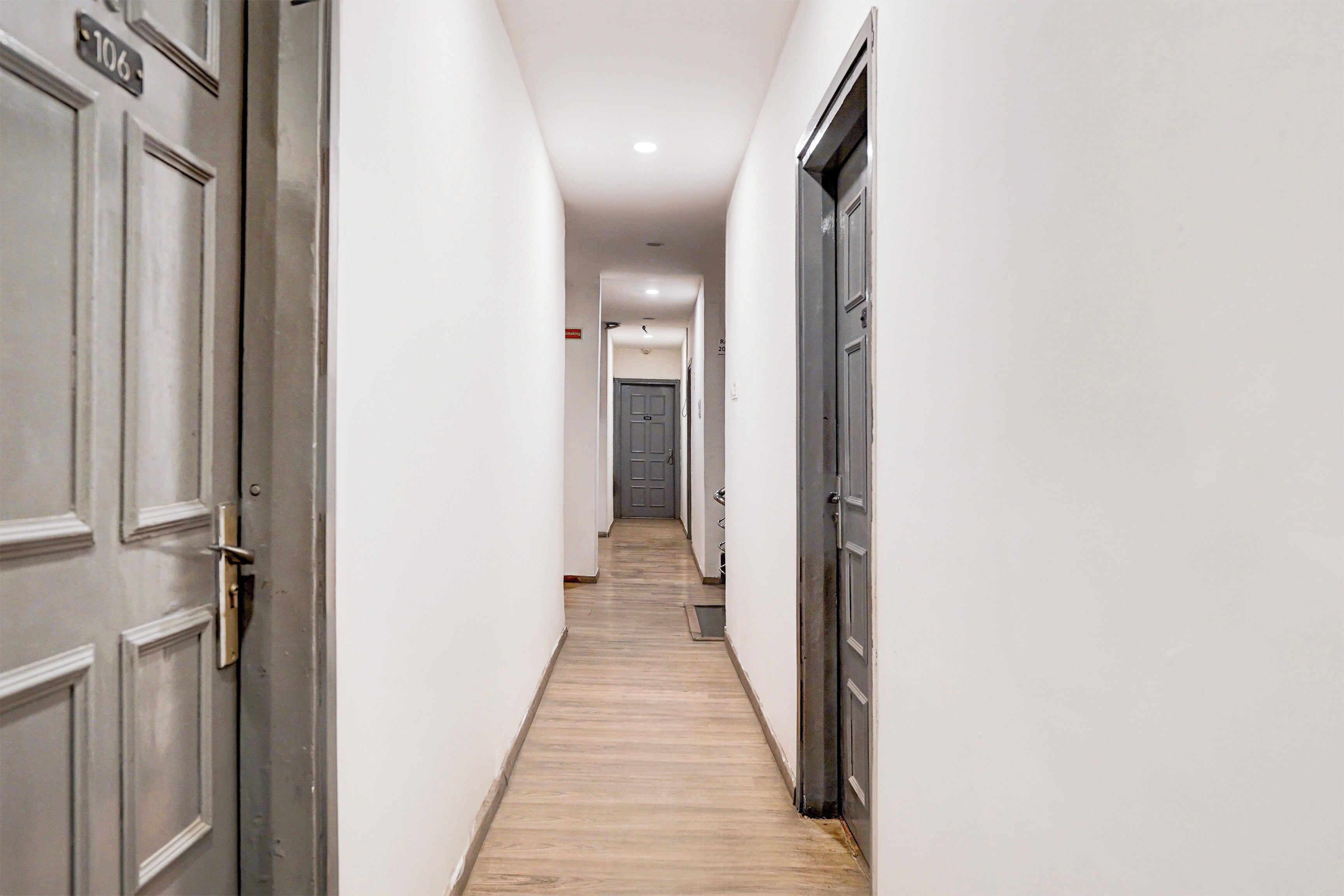 A hallway with doors on both sides, a wooden floor, and a ceiling with recessed lighting.