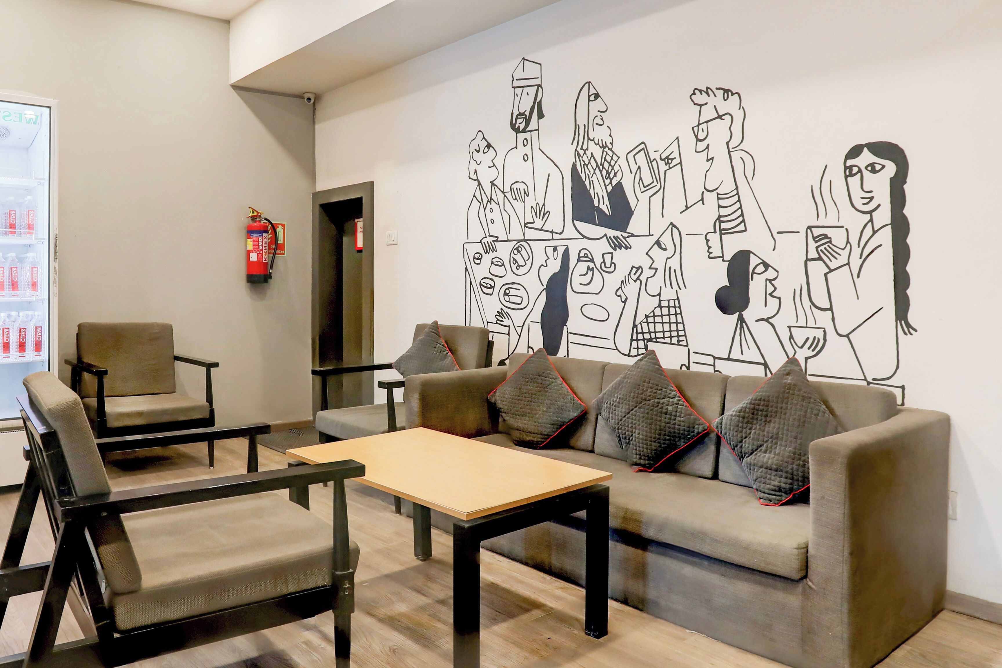A modern lounge area with a sofa, chairs, a coffee table, and a wall mural.