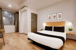 A hotel room with a bed, bedside table, lamp, and a window with curtains. - Townhouse Kalmana (Nagpur)