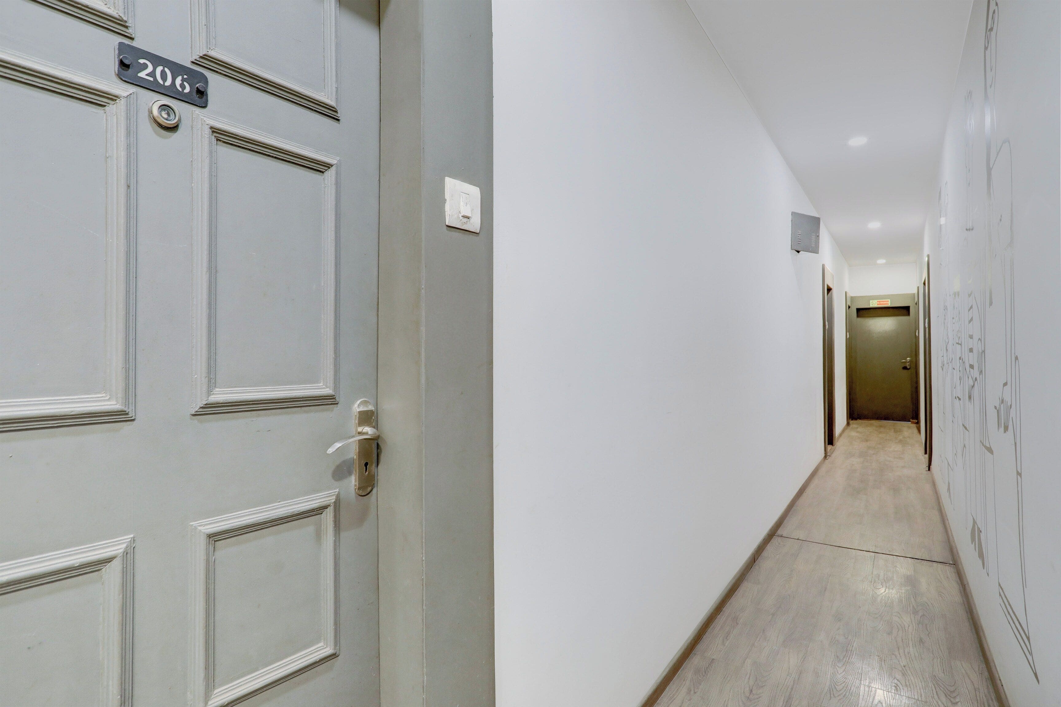 Passatge amb una porta marcada '206' i un interruptor a la paret.
